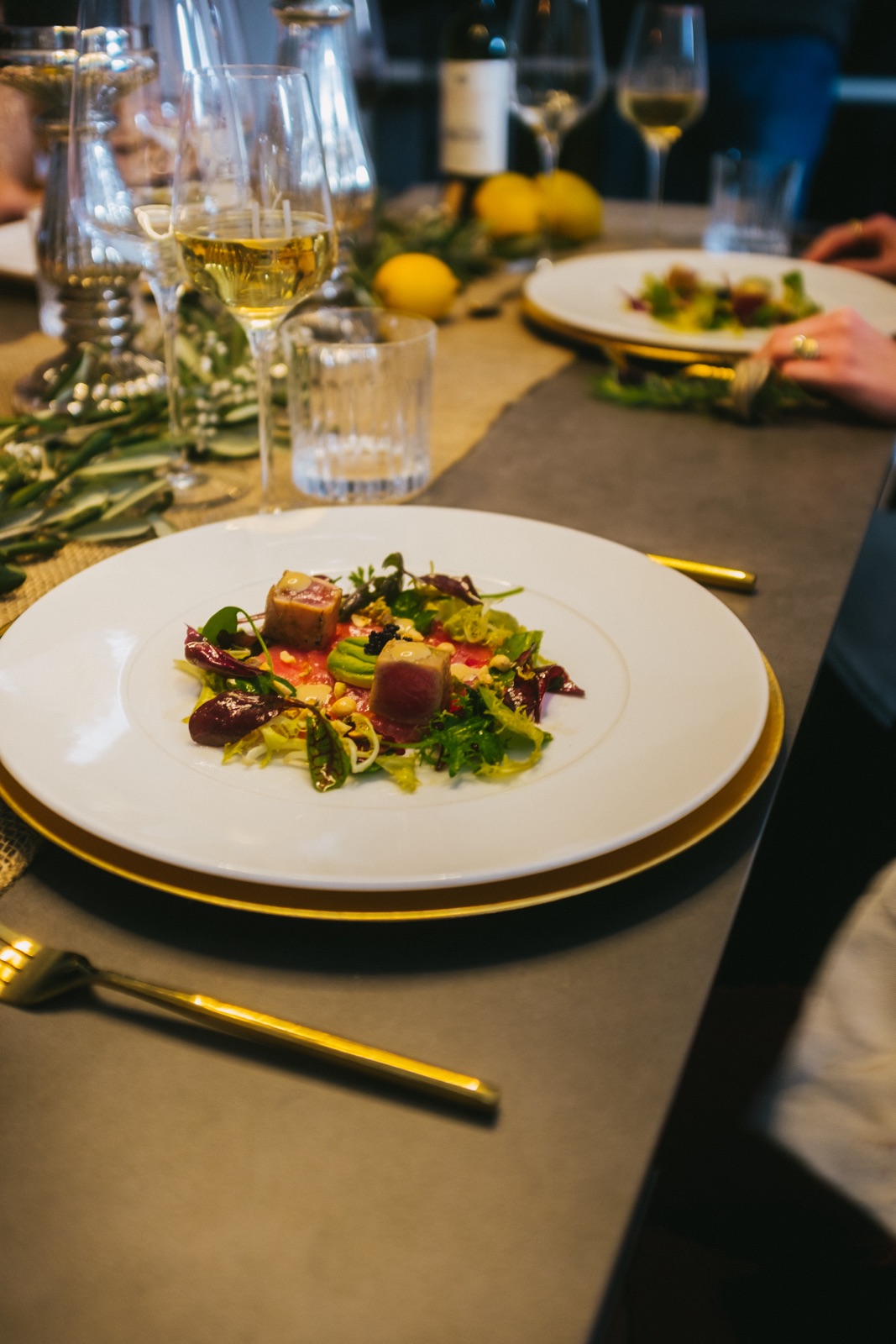 Gedeckter Tisch mit angerichteter Vorspeise und Weißwein bei einem gesetzten Menü