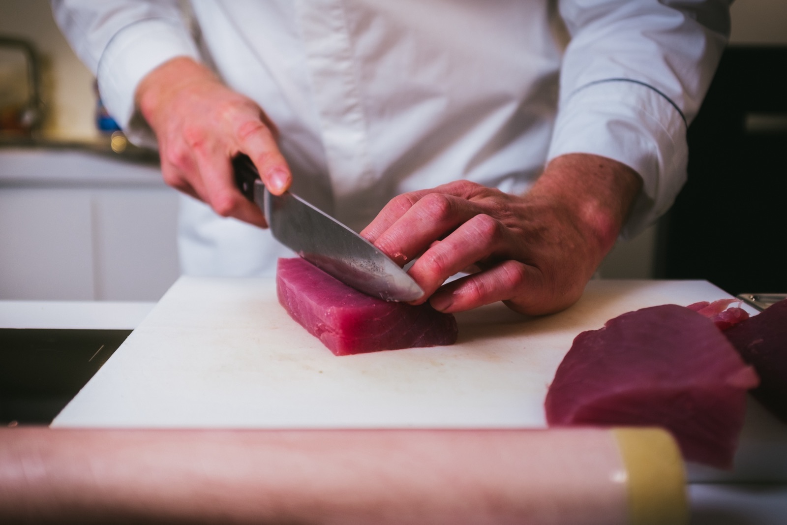 Thunfisch wird mit dem Kochmesser in Portionen geschnitten