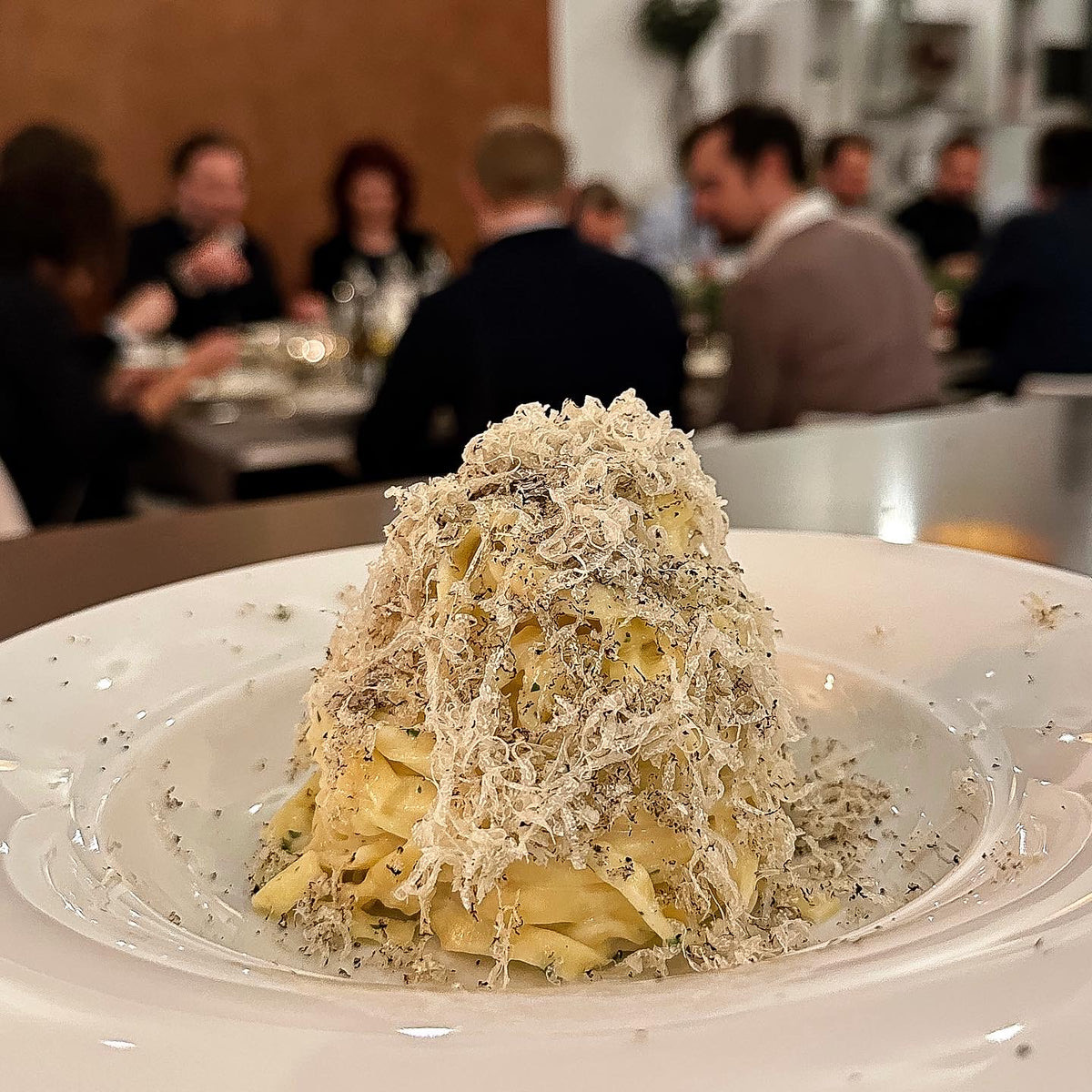 Tagliatelle mit Trüffel bei einer Firmenfeier, Gäste im Hintergrund